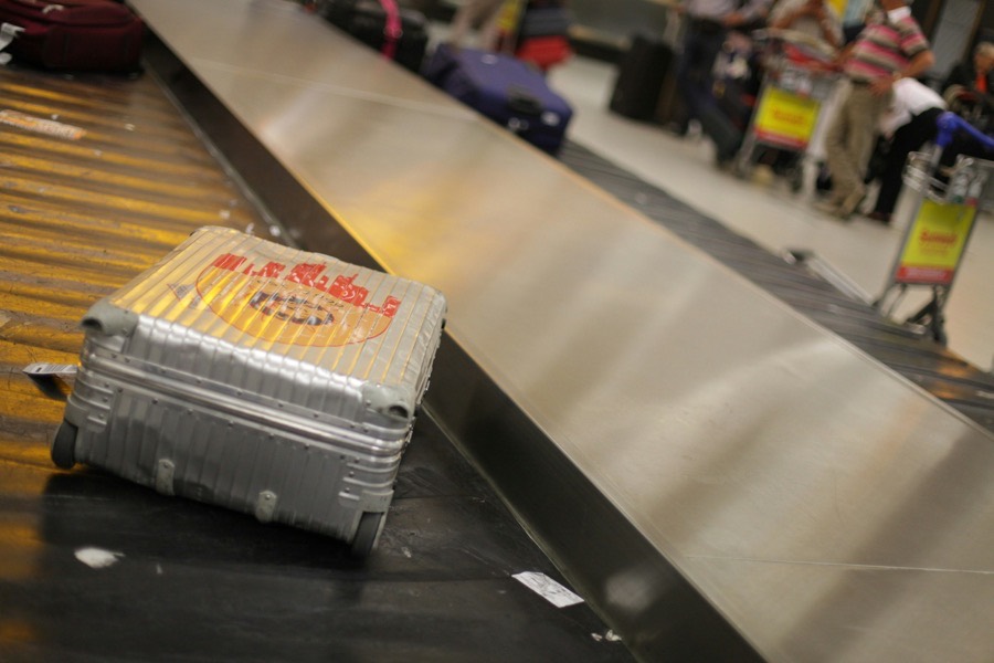 Valise sur un tapis à bagages d'aéroport, voyageurs flous en arrière-plan