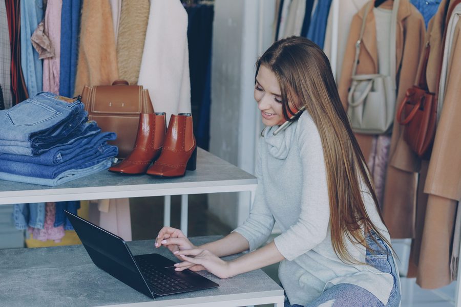 Commerçante travaillant sur un ordinateur portable dans une boutique de vêtements